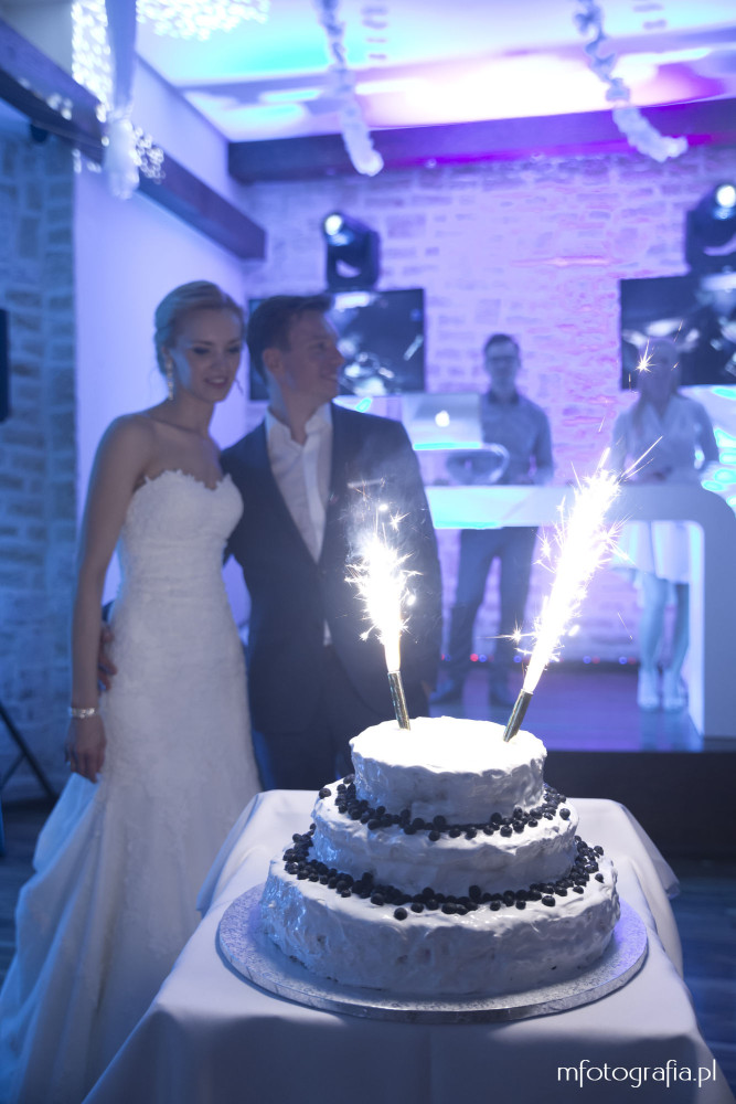 fotografia pary młodej przy torcie weselnym